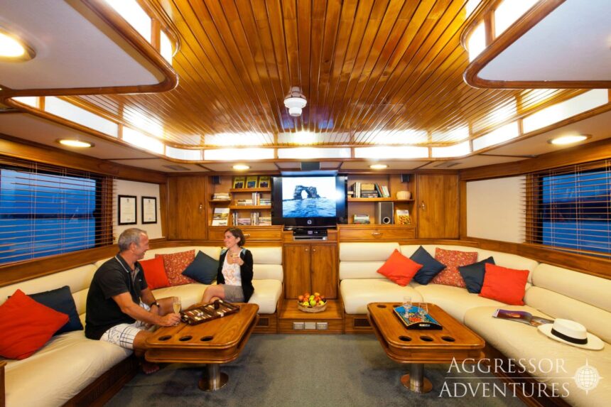 Guests play backgammon in the wood paneled salon of the Galapagos Aggressor III