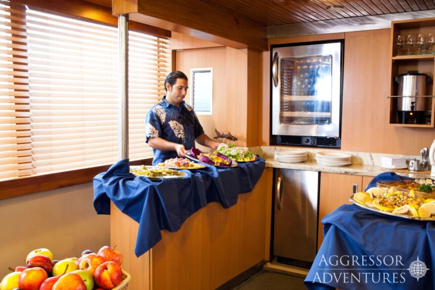 Crew member plates a seafood spread for guests aboard the Galapagos Aggressor III