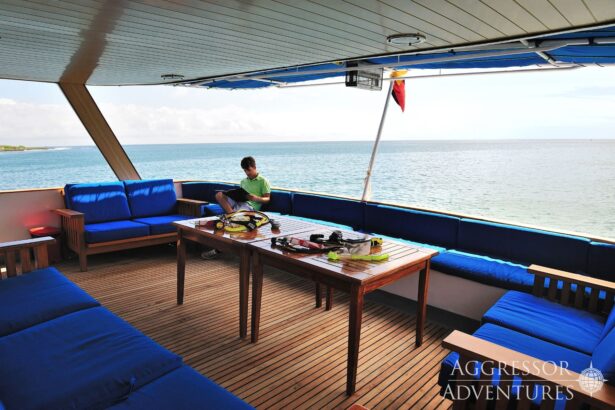 Guest reads on the covered sun deck with dive gear laid out on the table