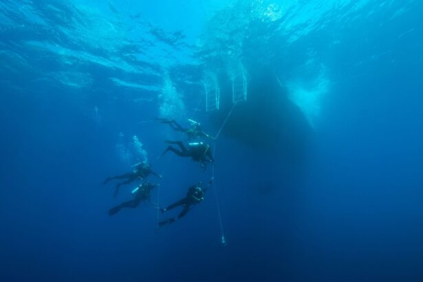 Divers descending along a line beneath the liveaboard's hull