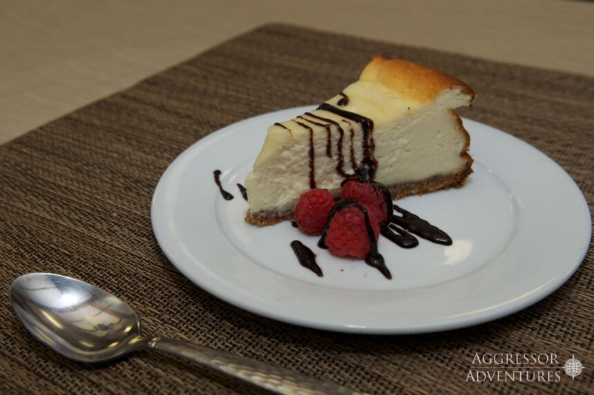 Slice of cheesecake with raspberries and chocolate drizzle served onboard