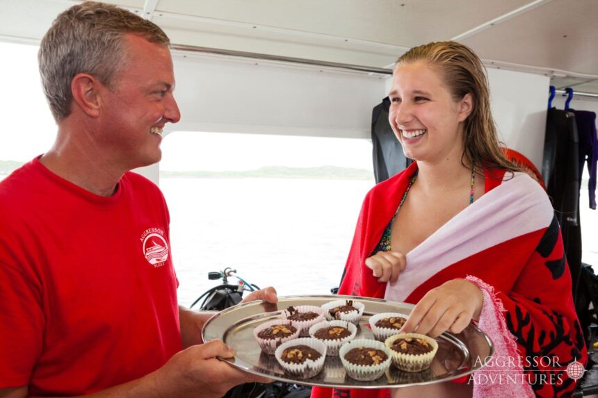 Crew presents a tray of cupcakes to a towel-wrapped diver after a dive