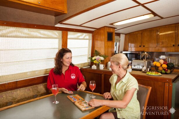Two crew members play a board game and share drinks in the salon
