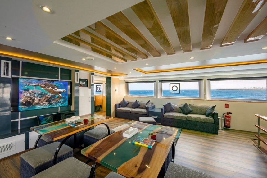 Lounge area aboard the Emperor Elite with sofas facing a large screen and windows