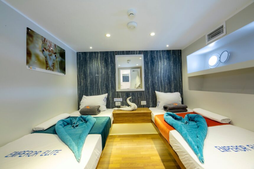 Wood-paneled twin cabin aboard the Emperor Elite with teal and orange linens