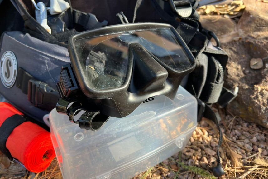 ScubaPro Gorilla Frameless mask propped on a clear gear box beside a ScubaPro BCD and red SMB