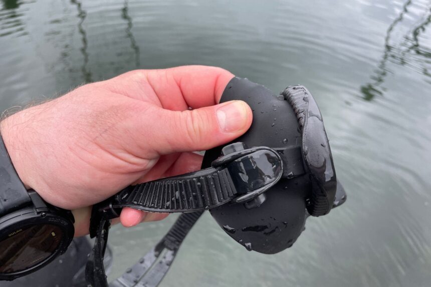 DIVEIN tester holding the wet Promate Spectrum mask by its strap buckle at the surface