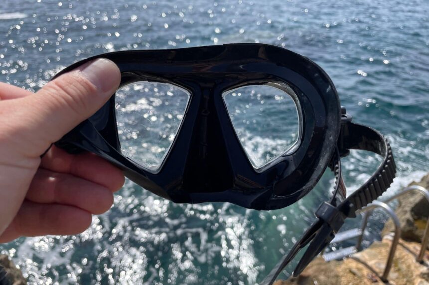 Promate Spectrum mask held against the sunlit sea, showing the bonded lenses from inside