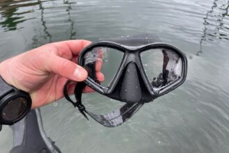 Our tester holding the wet Promate Spectrum prescription dive mask beside the water after a dive