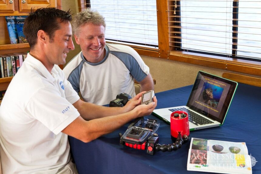 Two crew members reviewing underwater camera housing gear on a laptop aboard the Belize Aggressor III