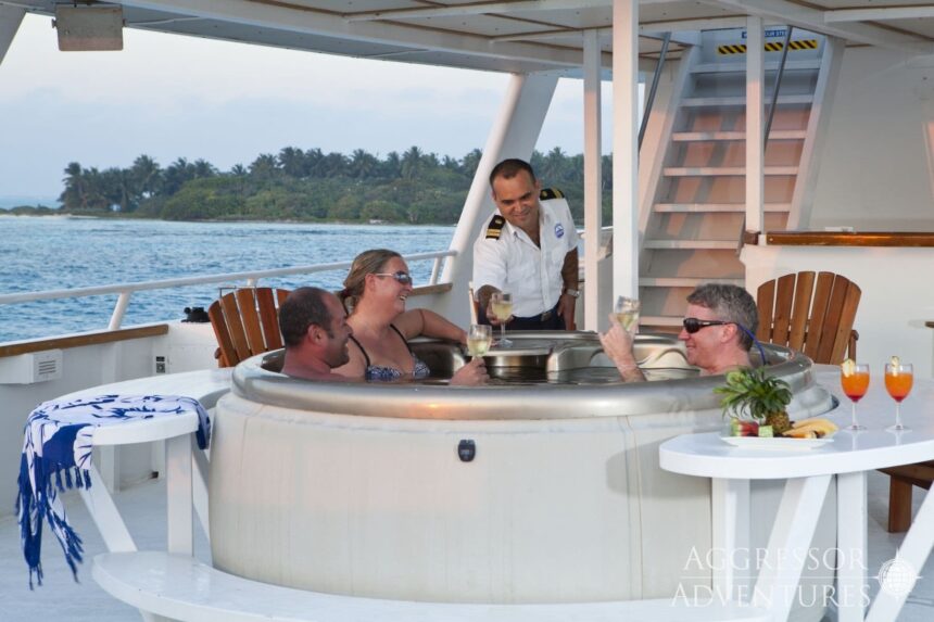 Guests in the hot tub on the Belize Aggressor III sun deck as a crew member serves drinks