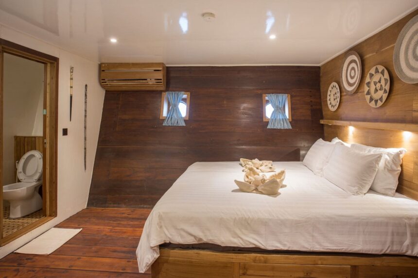 wood paneled cabin with a large bed decorated with folded towel art