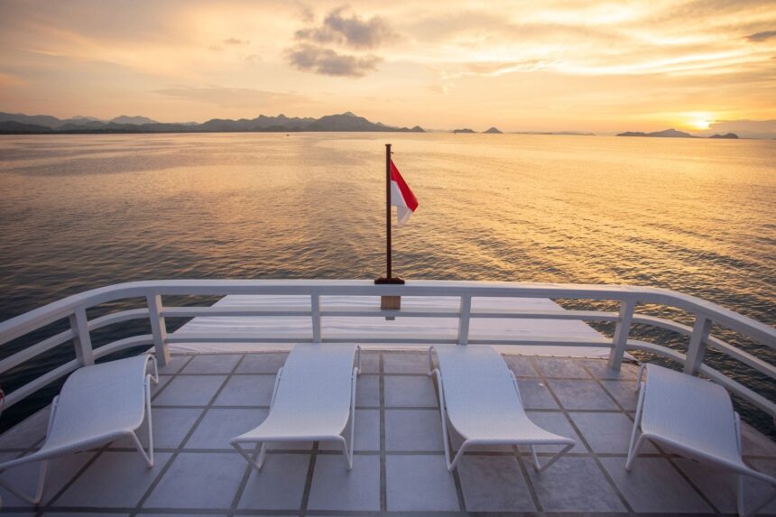 sun loungers on the bow of a liveaboard at sunset with a flag flying