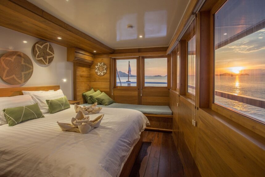 liveaboard cabin with a double bed and large windows overlooking the sunset sea