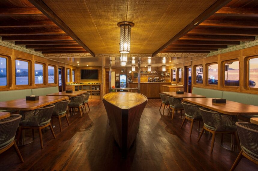 wood paneled dining room on a liveaboard with tables and rattan chairs