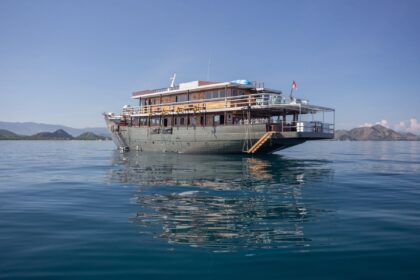 Emperor Harmoni liveaboard phinisi anchored in calm water with its reflection