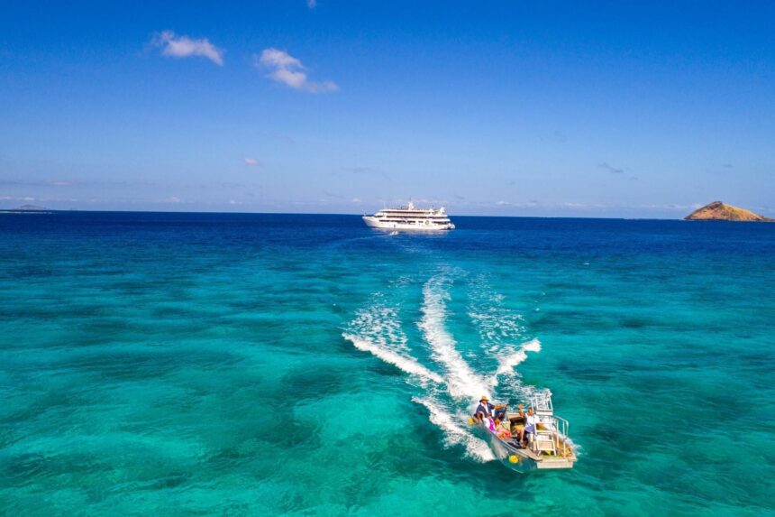 Fiji Princess liveaboard anchored at dusk with a paddleboarder nearby