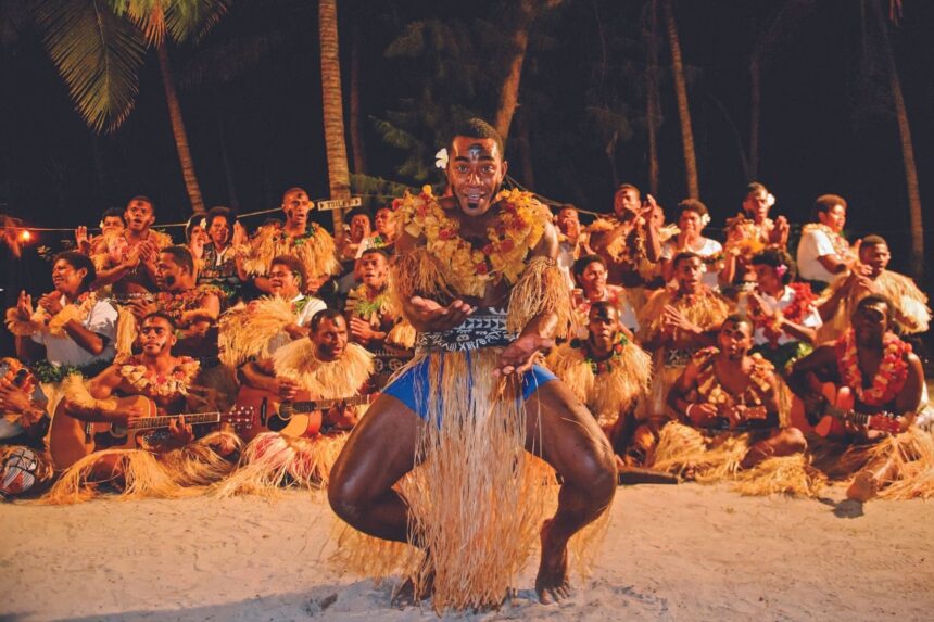 Fijian dancer performing a torch lit meke for cruise guests on the beach