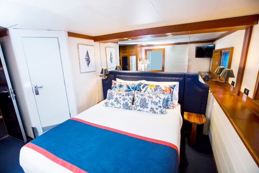 queen bed with tropical print pillows in a Fiji Princess cabin