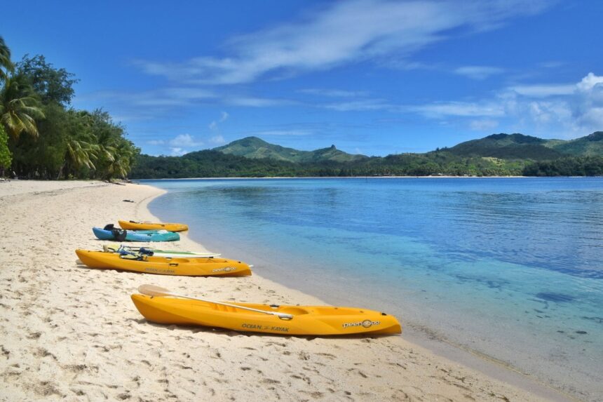 yellow and green kayaks lined up on a white sand Fiji beach
