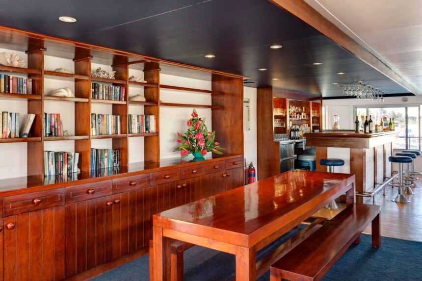 wood shelving stocked with books beside a dining table aboard the Fiji Princess