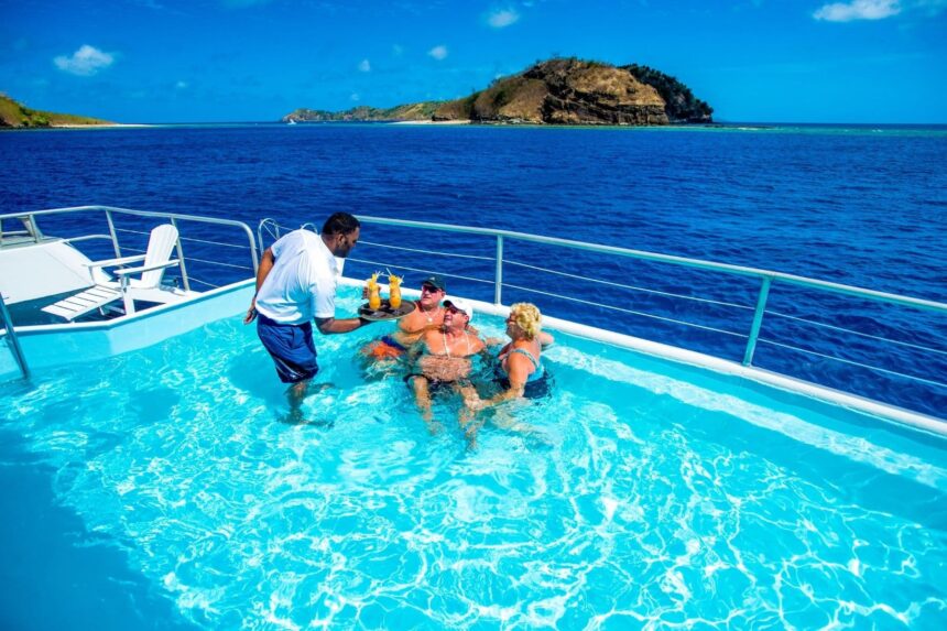 crew member serving cocktails to guests relaxing in the Fiji Princess's onboard pool