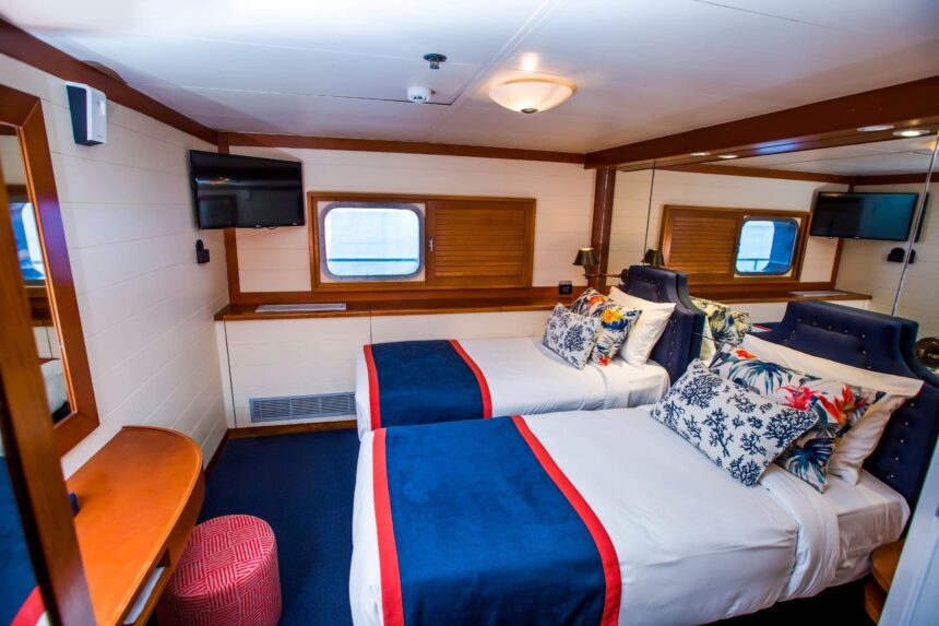 twin cabin with navy and white bedding aboard the Fiji Princess