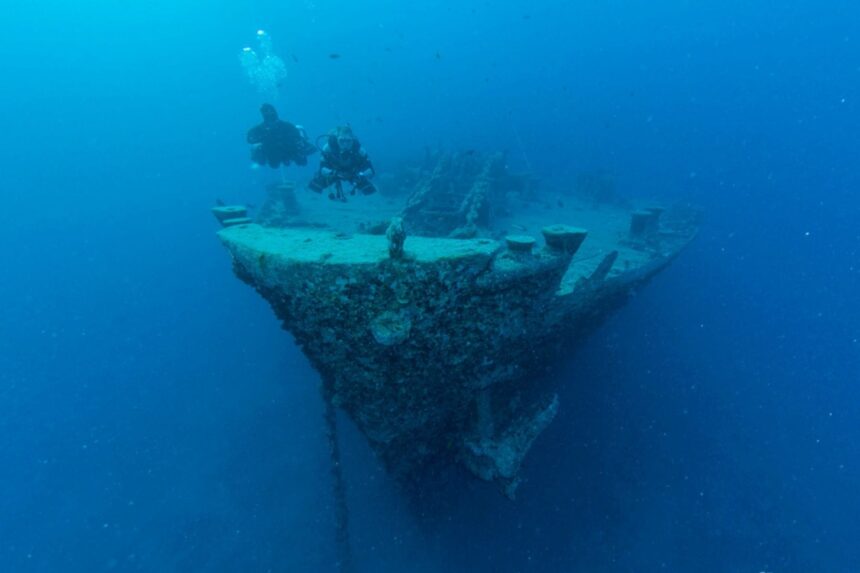 Two divers hovering above the bow of a sunken wreck