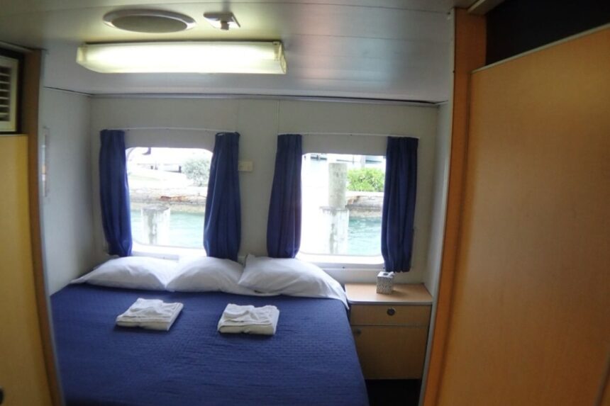 A made-up double cabin bed with folded towels aboard the Aqua Cat