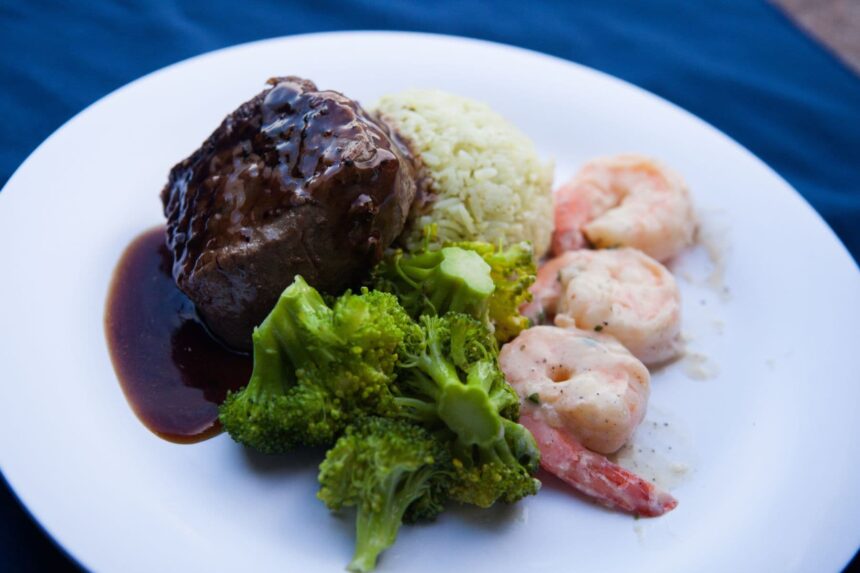 A plated dinner of steak, rice, shrimp, and broccoli served aboard the Aqua Cat