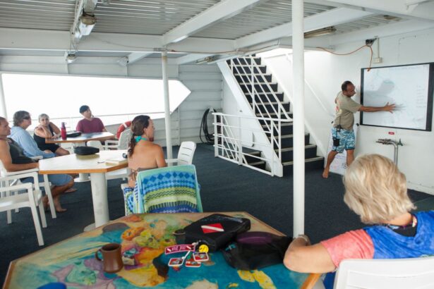 A crew member giving a dive site briefing on a whiteboard to seated guests