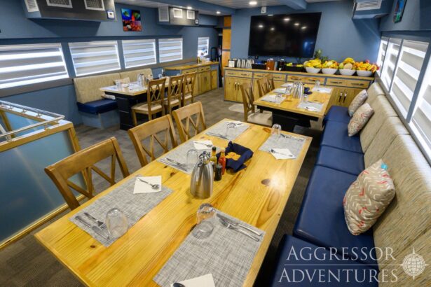 A wood-toned dining salon with set tables aboard the Cayman Aggressor IV