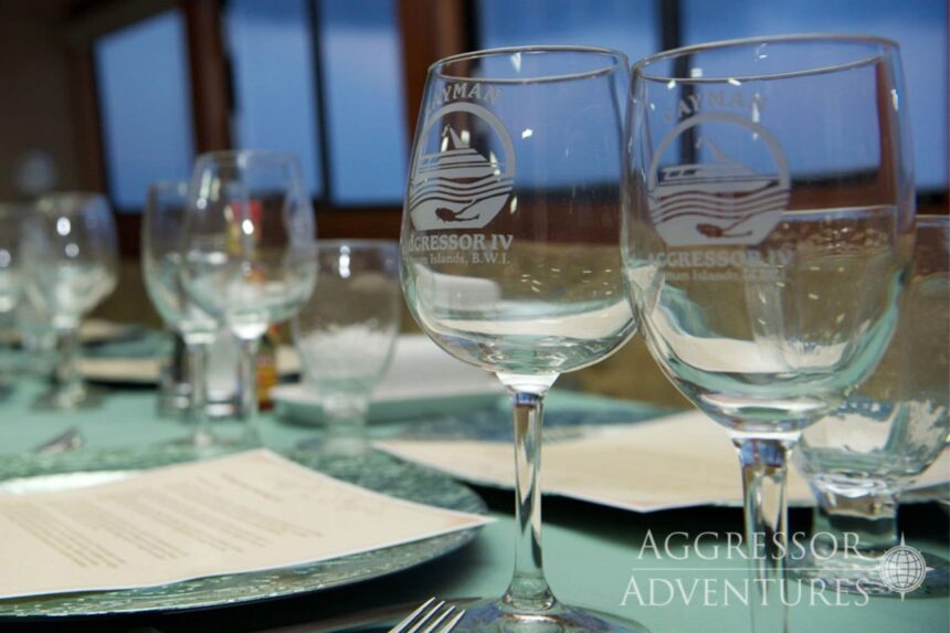 Wine glasses etched with the Cayman Aggressor IV logo set for dinner service