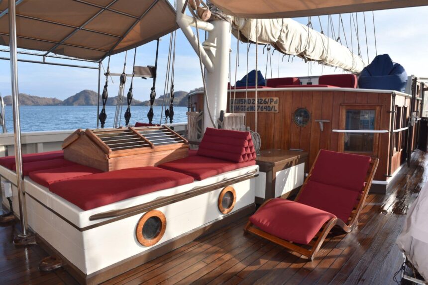 Red cushioned lounging area on the wooden deck of the Emperor Raja Laut schooner