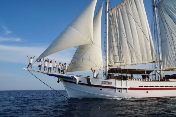 Crew and guests posing on the bowsprit of the Emperor Raja Laut with sails raised