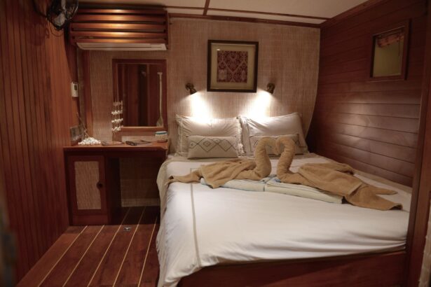 Wood-paneled cabin aboard the Emperor Raja Laut with a bed decorated with folded towel swans