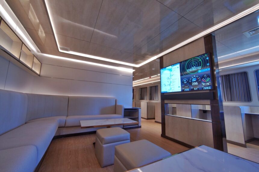 Modern lounge aboard the All Star Velocean with a wall-mounted navigation display