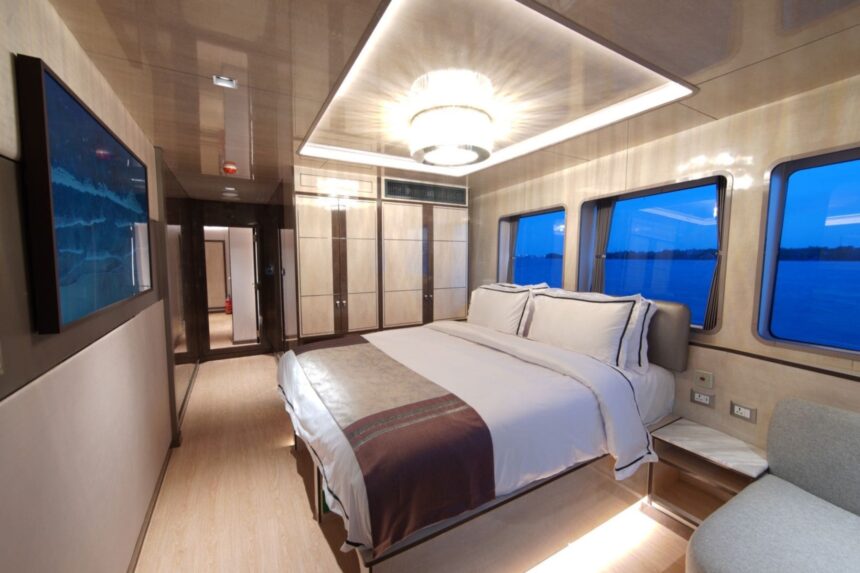 Suite bedroom aboard the All Star Velocean with a large bed and wall-mounted TV