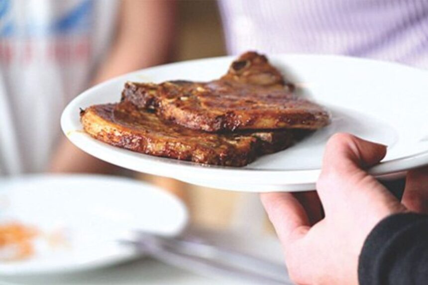 Server carrying a plate of grilled ribs aboard the All Star Velocean