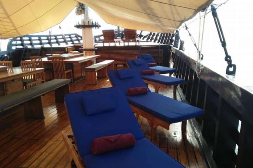 blue cushioned sun loungers with rolled towels on the Amira's deck