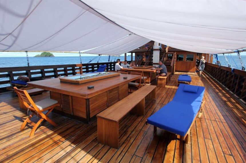 covered dining area with wooden tables and benches on the Amira liveaboard deck