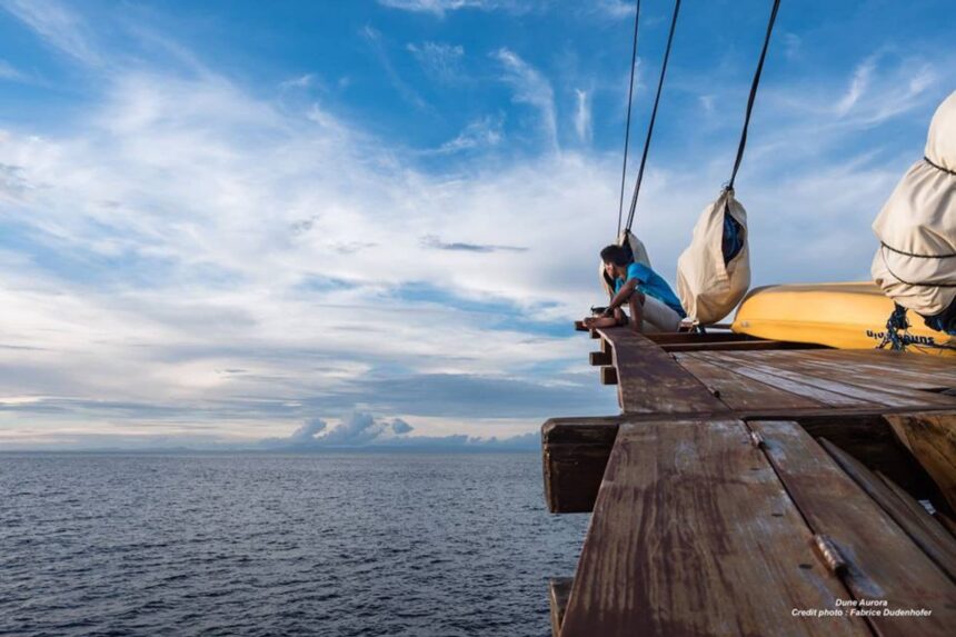 guest relaxing on the bowsprit platform of the Aurora at sunset