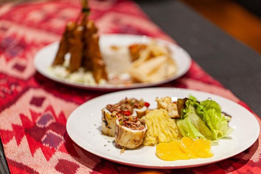 Two plates of grilled seafood and vegetables served on a liveaboard dining table