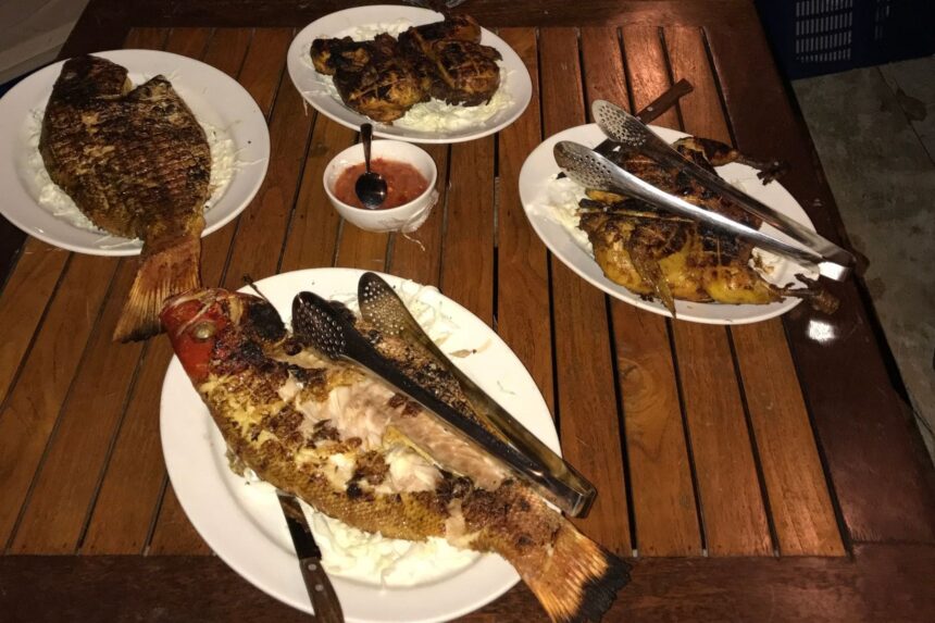 plates of grilled whole fish and chicken served on board