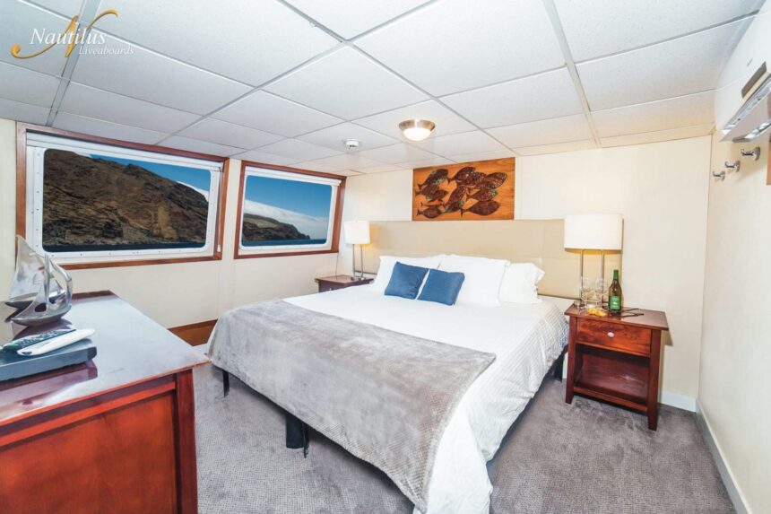 Guest stateroom on the Nautilus Explorer with a king bed and twin ocean-view windows