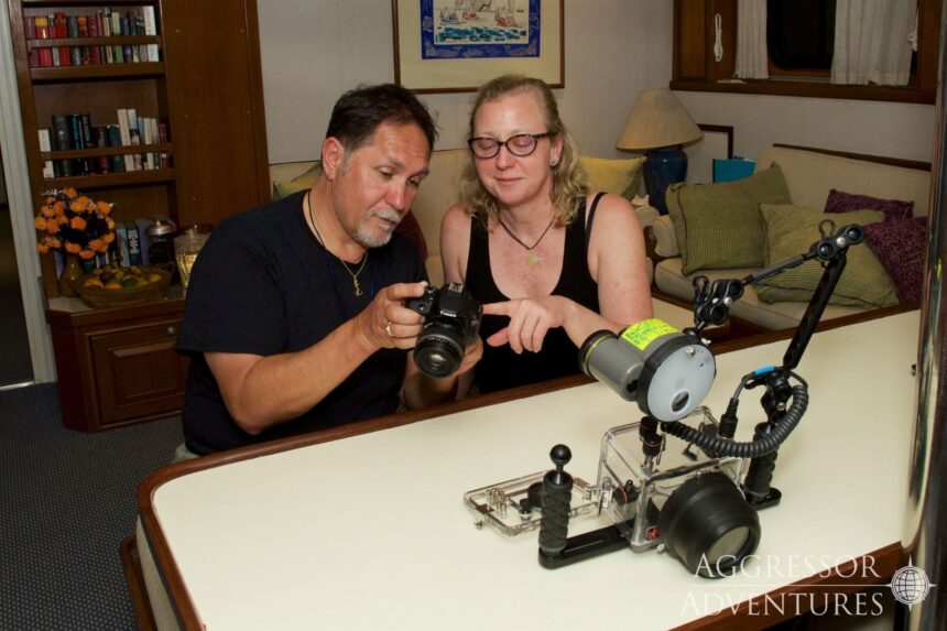 Guests review underwater camera housing footage together in the salon of the Raja Ampat Aggressor