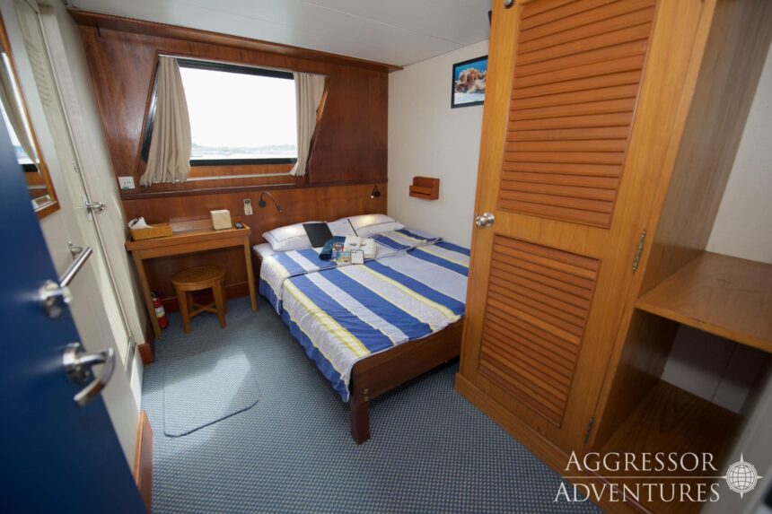 A stateroom aboard the Raja Ampat Aggressor with a striped bed and wardrobe