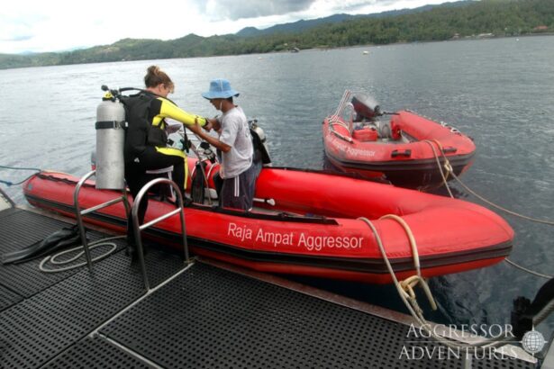 Divers gear up on a red inflatable tender boat labeled Raja Ampat Aggressor