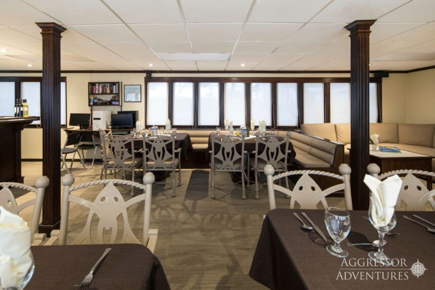 Dining and lounge area with table settings aboard the Okeanos Aggressor II