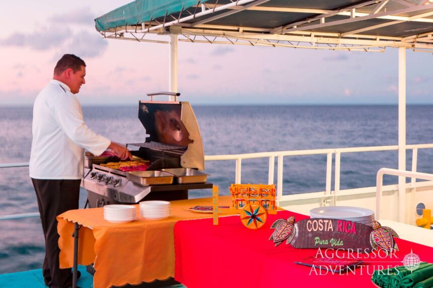 Crew member grilling food at sunset on the Okeanos Aggressor II deck